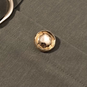 Macro detail of olive green twill fabric featuring a decorative gold metallic button