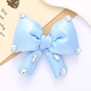 Elegant blue satin bow hair accessory with sparkling rhinestones on a white background