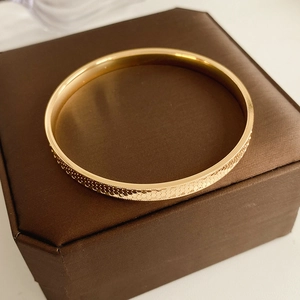 Detailed close-up of golden metal cuff bracelet with scale-like honeycomb pattern texture