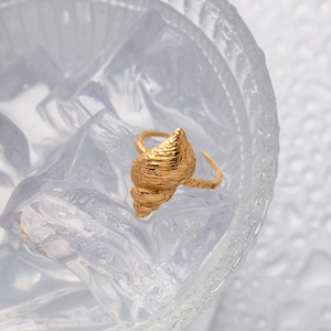 Detailed view of a golden conch ring with sea shell texture placed on clear ice cubes
