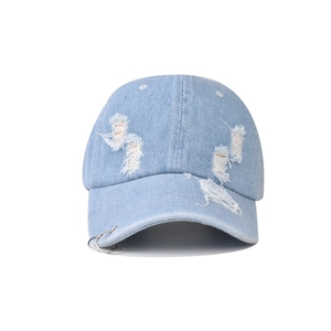 Detail of distressed light blue denim baseball cap with metal rings and frayed holes