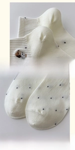 Macro view of white polka dot socks with dog embroidery and reinforced heel design