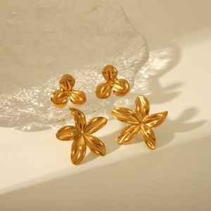 Détail de boucles d'oreilles fleurs en or 18k avec motifs à trois et cinq pétales