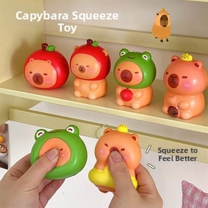 Close-up of cute capybara squeeze toys in frog and apple hats for stress relief