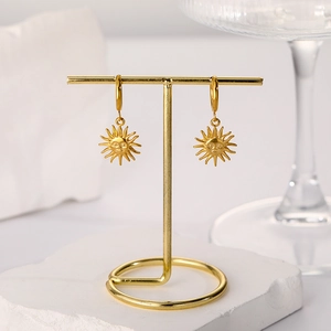 Close-up of vintage 18k gold plated sun face charm hoop earrings on a display stand