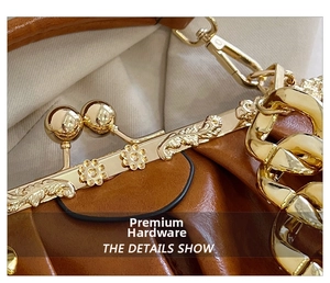 Macro detail of retro brown handbag featuring embossed floral gold clasp and thick metal chain