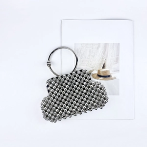 Close-up of a silver beaded shell bag with a round metal handle on a magazine background