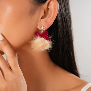 Detail of snowflake pendant earrings with red velvet bows and fur balls on a model