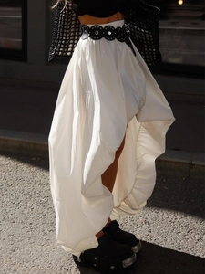 Détail de la jupe asymétrique blanche en coton avec ceinture à œillets et ourlet à couches