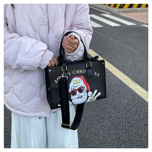 Detailed view of black Santa Claus tote bag with Merry Christmas print on outdoor street