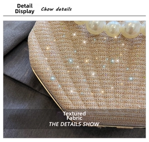 Macro shot of glittery champagne fabric and large pearl decoration on shell bag