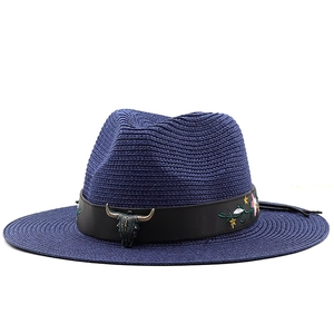 Dettaglio cappello di paglia blu con decorazione a testa di toro e ricamo floreale
