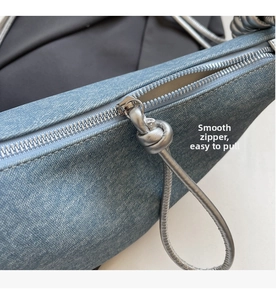 Detail of smooth silver zipper with knot puller on light blue denim saddle bag