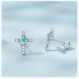 Macro shot of silver cross stud earrings with turquoise stones and small white diamonds
