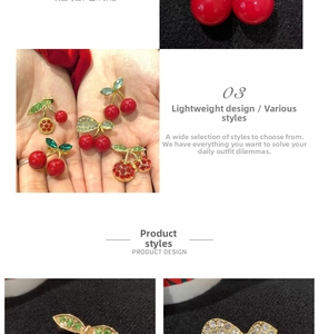Detail of cherry brooch featuring red enamel fruits and green rhinestone inlaid leaves