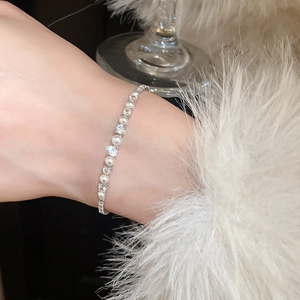 Close-up of pearl and zircon bracelet on wrist featuring elegant metal details