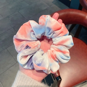 Pink and blue tie-dye velvet scrunchie held in hand showing soft texture and size