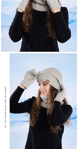 Detail of light grey cable knit beanie, scarf and gloves set with a brown leather logo tag