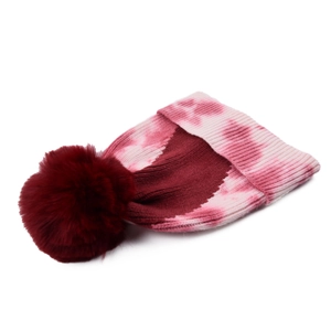 Detail of winter tie-dye knit beanie with fluffy burgundy faux fur pompom and cuff