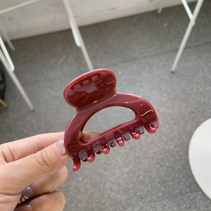 Detailed view of glossy burgundy butterfly hair claw clip with smooth curved design
