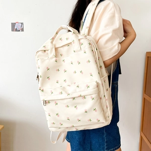 Floral backpack with pink roses worn by a model against a clean minimalist wall
