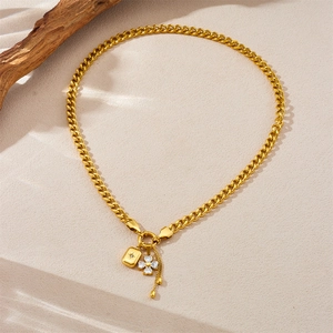 Detail of gold chunky Cuban chain necklace with star lock and clover charms on wood