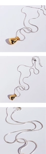 Detail view of two-tone teardrop pendant on a silver snake chain necklace