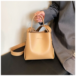 Close-up of a camel leather bucket bag showing fine texture and a brand logo detail