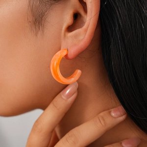 Detailansicht eines orangefarbenen C-förmigen Acryl-Creolenohrrings getragen am Ohr