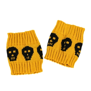 Close-up of yellow knitted leg warmers with black skull patterns on white background