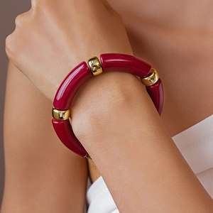 Dettaglio del bracciale in resina bordeaux con distanziatori dorati al polso del modello