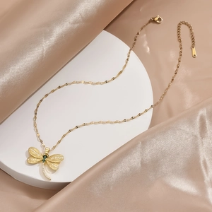 Elegant gold dragonfly necklace with green zircon and sparkling crystals on silk background