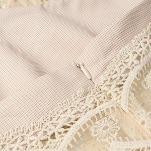 Détail du tissu à carreaux beige avec bordure en dentelle blanche et fermeture éclair