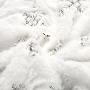 Close-up of white plush Christmas tree skirt with silver sequin snowflake embroidery