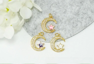 Macro view of 18K gold plated moon and star pendants with pavé zircons and colorful enamel