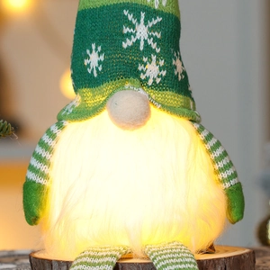 Close-up of glowing Christmas gnome with snowflake knit hat and plush beard on wood