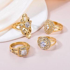 Detailed view of four vintage gold rings with zircon stones on white silk fabric