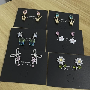 Macro shot of assorted crystal stud earrings with tulip and daisy designs on wood