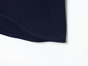 Détail de la texture du tissu tissé bleu marine avec couture double précise sur l'ourlet
