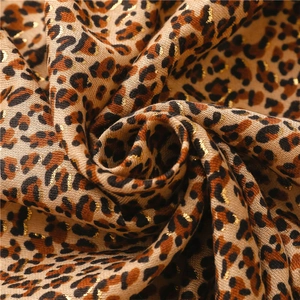 Detailed macro view of leopard print scarf fabric with sparkling golden metallic threads