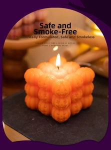 Detailed view of orange pumpkin cube candle with stacked skull textures for Halloween decor