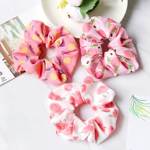 Detail of soft fabric scrunchies with pink lemon and peach fruit patterns on marble