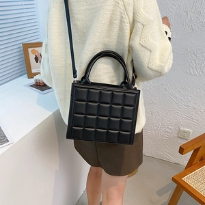 Classic black quilted vertical square handbag with adjustable shoulder strap and top handles