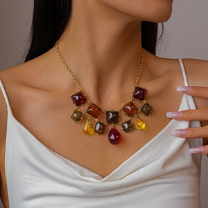 Gros plan du collier géométrique en résine avec pendentifs goutte rouge foncé et ambre