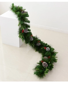 Detail of Christmas garland with pine needles, frosted cones and red berries on white base