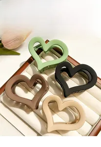 Close-up of four matte heart-shaped claw clips in green, black, brown, and cream tones