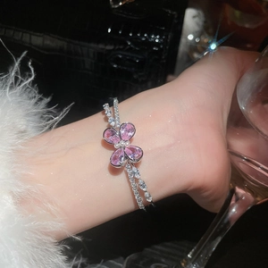 Macro detail of silver double-layered bracelet with pink zircon butterfly and pearl