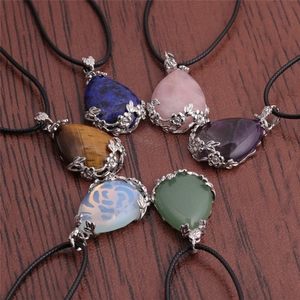 Set of six water drop crystal necklaces with floral metal wrap on a wooden background