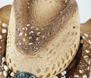 Detail of hollow woven straw cowboy hat with vintage turquoise bead and metal ornament