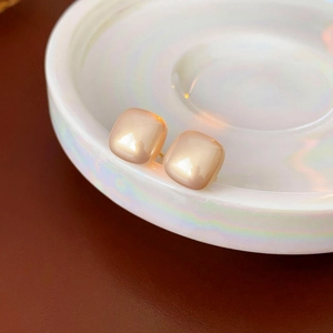 Macro shot of 14K gold plated square pearl stud earrings with iridescent luster on a tray